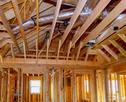 Installation under construction with wooden beams of HVAC tubing vents heating system on the roof,