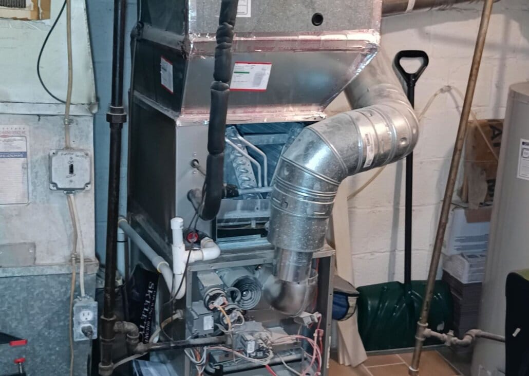 Basement furnace and ductwork with visible wiring and pipes.