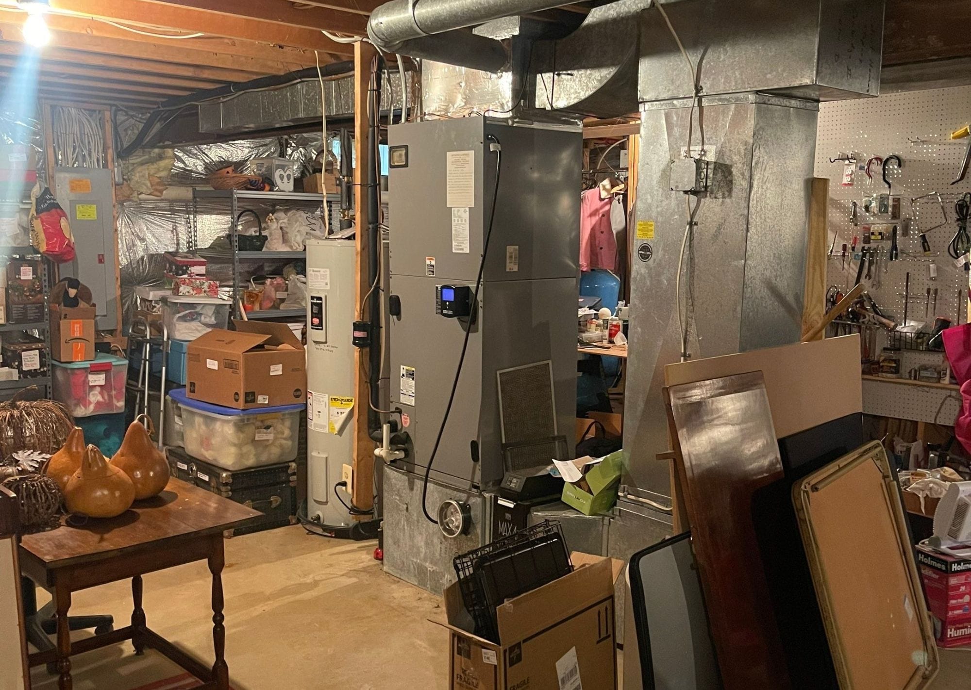 Basement furnace and water heater surrounded by storage boxes.