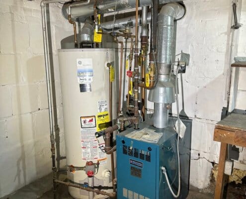Basement water heater and furnace with connected metal piping.