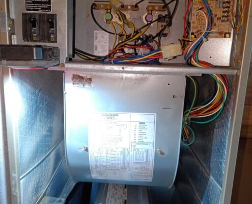 Open electrical furnace panel showing wiring, breakers, blower motor, and components.
